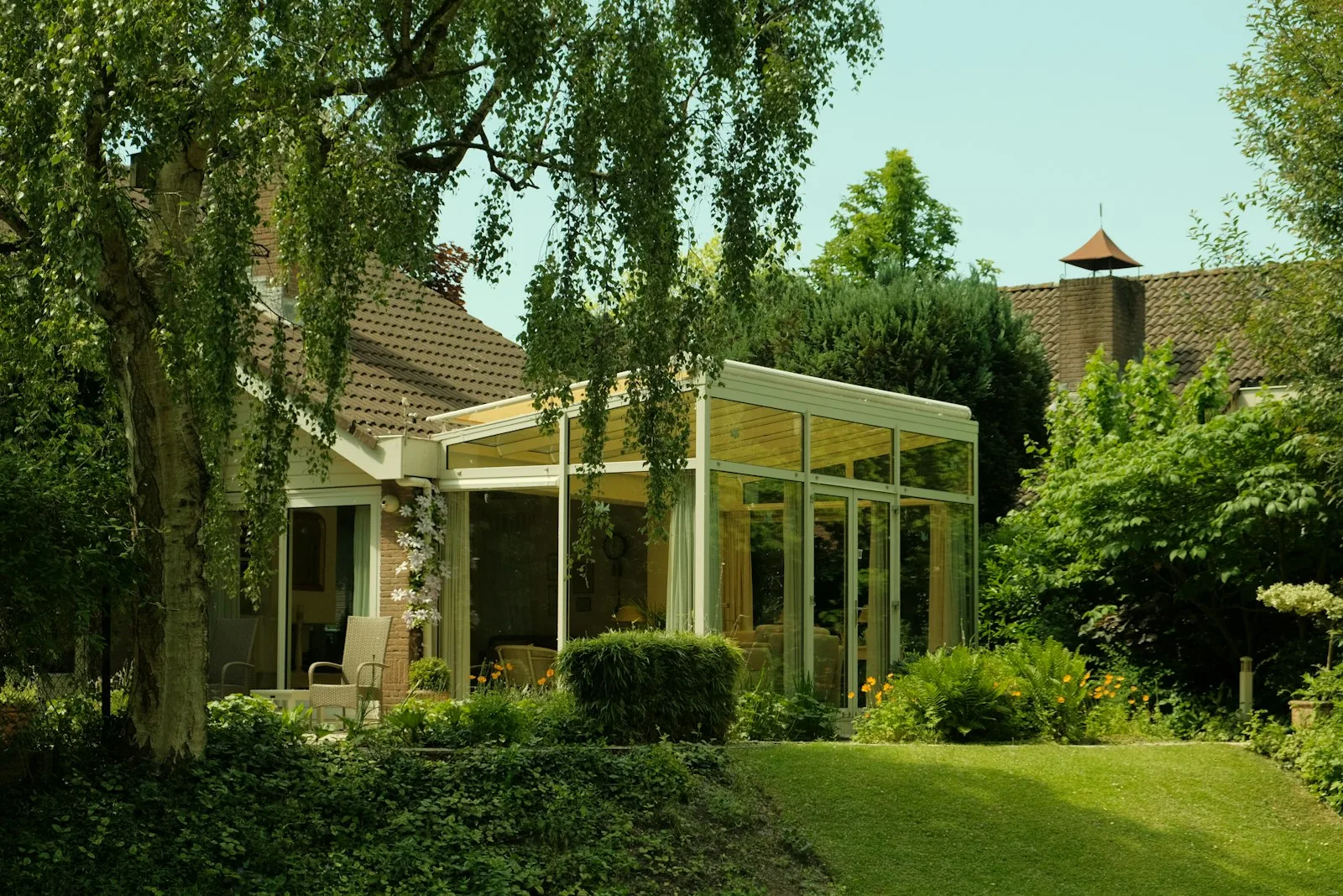 Glass-walled home extension opening onto a manicured garden