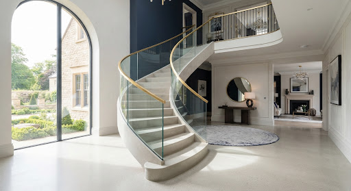 Sweeping staircase with glass balustrade and gold detailing