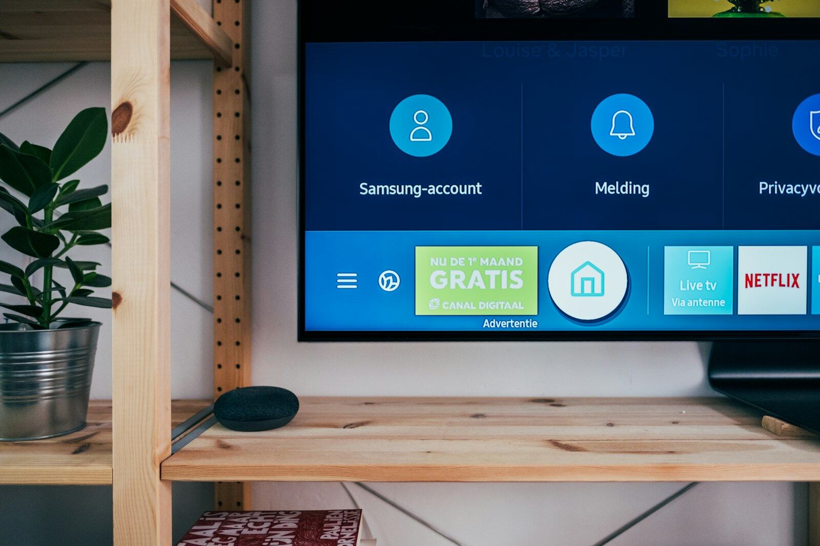 Wall-mounted smart TV with a voice speaker on a shelf