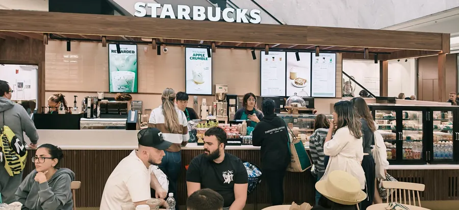 Completed Starbucks kiosk counter with walnut canopy, menu screens and tiled back wall