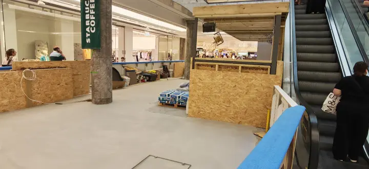 Wide site view showing floor preparation and temporary protection around the kiosk